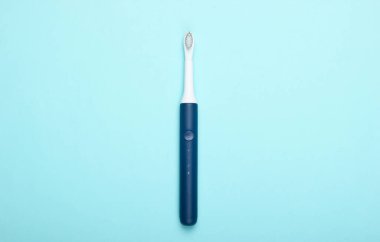 Mavi pastel arka planda modern elektrikli diş fırçası. Üst Manzara. Diş bakımı. Minimalizm