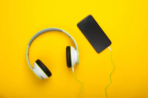 黄色の背景にスマートフォンと有線ステレオヘッドフォン 千年物だ 音楽好き 最上階だ ミニマリズム — ストック写真