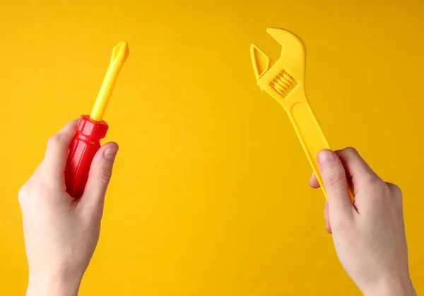 Mãos Segurando Uma Chave Fenda Brinquedo Chave Fundo Amarelo — Fotografia de Stock
