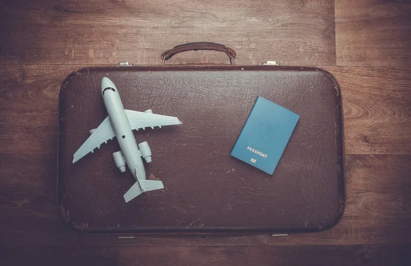 Travel concept. Old luggage, airplane figurine, passport on wooden floor. Flight voyage, trip, journey. Flat lay composition. Top view