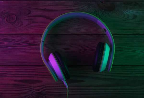 Retro stereo headphones with neon purple green light. Gradient glow. Top view