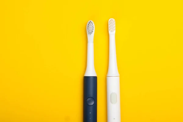 Zwei Moderne Elektrische Zahnbürsten Auf Gelbem Hintergrund Ansicht Von Oben — Stockfoto