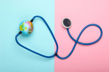 Küresel salgın sorunu. Pembe mavi arka planda steteskop ve küre. Küresel salgın. Üst görünüm
