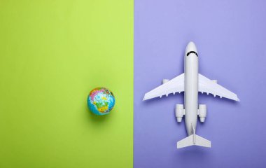 Turizm ve seyahat konsepti. Göçmenlik bürosu. Mor yeşil arka planda dünya ve yolcu uçağı figürleri. Üst Manzara. Düz yatıyordu