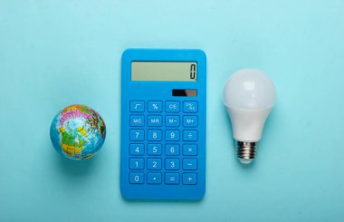 Enerji tasarrufu. Mavi pastel arka planda kurşun ampul ve küre ile hesap makinesi. Gezegeni kurtar. Eko konsepti. Üst görünüm