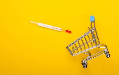Sarı arka planda termometresi olan bir alışveriş arabası. Sıcak indirimler. Süpermarket. Üst görünüm