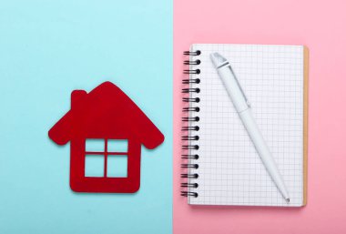 Konut kirası. Mavi-pembe pastel arka planda kalemli ev biblosu ve defter