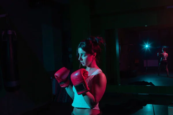 若いです女性ボクサーでボクシング手袋でネオングラデーション赤青光で暗い背景 — ストック写真