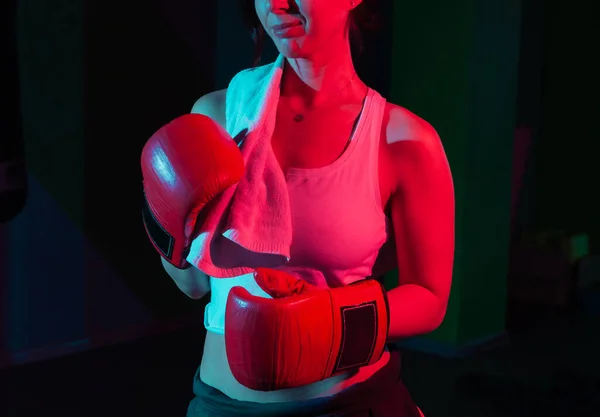 ボクシンググローブの若い女性ボクサーと暗い背景に彼女の肩のタオル ネオングラデーションレッドブルーライト — ストック写真