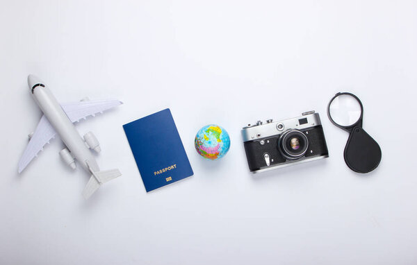 Tourism and travel concept. Globe, camera, passport, passenger plane figurine on white background. Top view. Flat lay