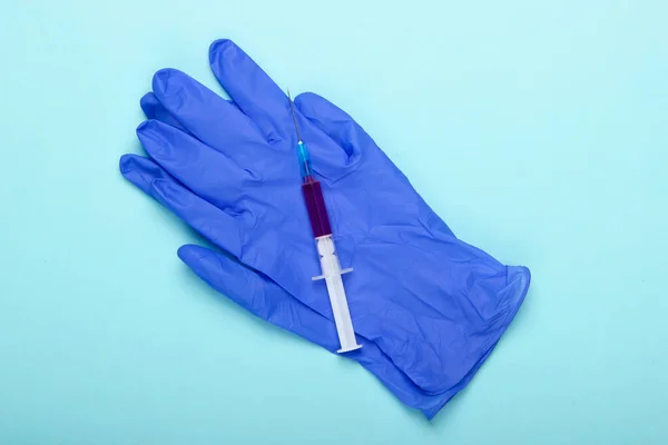 青い背景にブルーのラテックス手袋と注射器 予防接種だ トップ表示 — ストック写真