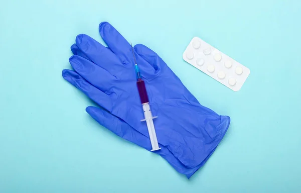 青い背景に青いラテックス手袋 注射器 予防接種だ トップ表示 — ストック写真