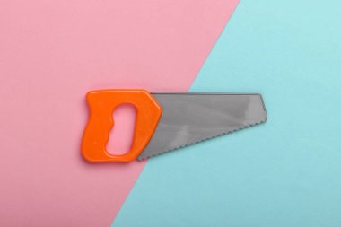 Mavi-pembe renkli arka planda küçük plastik bir testere. Üst görünüm