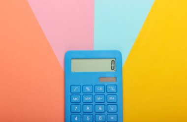 Renkli pastel arka planda mavi hesap makinesi. Hesaplama ya da sayım. Minimalizm. Üst görünüm