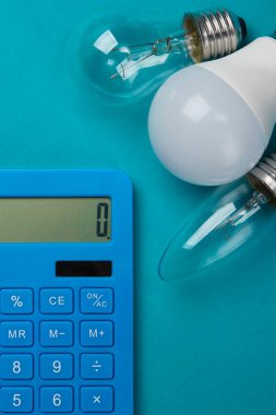 Enerji tasarrufu. Mavi arka planda ampulleri olan bir hesap makinesi. Üst görünüm