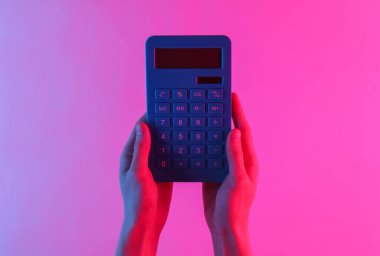 El ele tutuşan, neon mavisi, pembe gradyan ışığı olan hesap makinesi. Üst görünüm