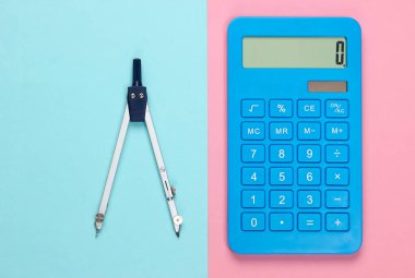 Pembe mavi pastel arka planda hesap makinesi ve pusula. Üst görünüm