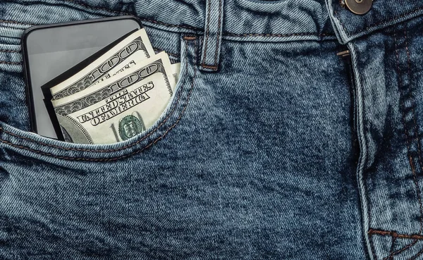 百元钞票和一部智能手机在蓝色牛仔裤的前袋特写 — 图库照片