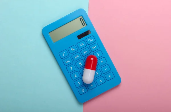 Calculation of the cost of medical expenses. Calculator and pill on a blue-pink pastel background. Top view. Minimalism