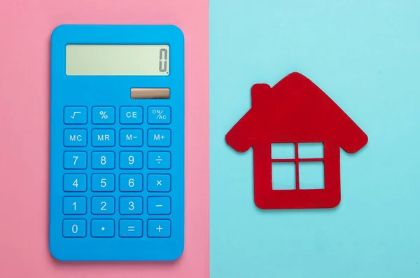 Calculation of the cost of rental housing. Red house figurine, calculator on pink blue pastel background. Top view