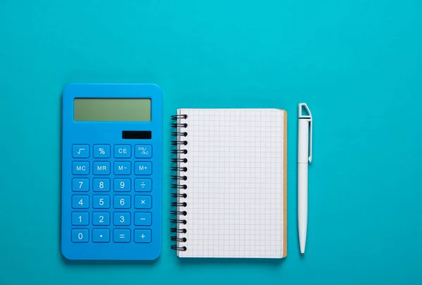 Calculator with notebook on blue background. Education process. Top view. Flat lay
