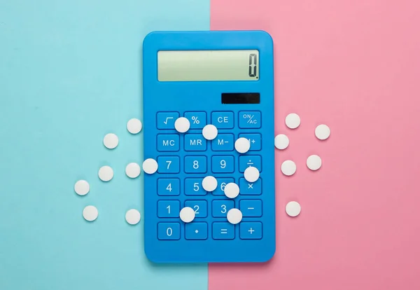 Calculation of the cost of medical expenses. Calculator and pills on pink blue pastel background. Top view. Minimalism