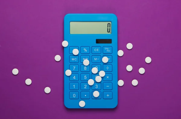 Calculation of the cost of medical expenses. Calculator and pills on purple background. Top view. Minimalism
