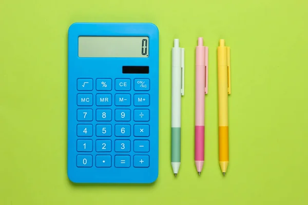 Blauwe Rekenmachine Met Gekleurde Pennen Een Groene Achtergrond Bovenaanzicht Kantoorgereedschap — Stockfoto