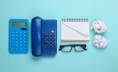 Mavi pastel arka planda ofis malzemelerinin düz kompozisyonu vardı. Üst görünüm