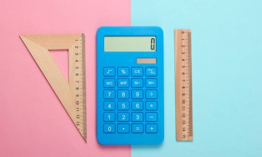 Hesap makinesi ve tahta cetvel, mavi-pembe pastel arka planda üçgen. Eğitim konsepti. Üst görünüm