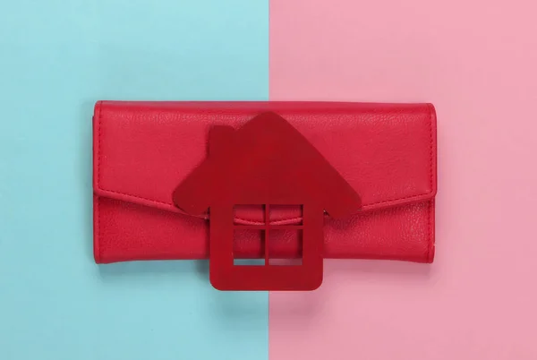 Family budget management. Figurine of a house with wallet on pink blue pastel background. Top view