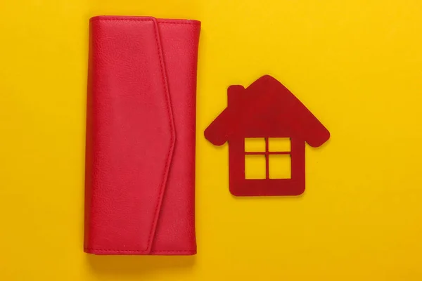 Family budget management. Figurine of a house with wallet on yellow background. Top view