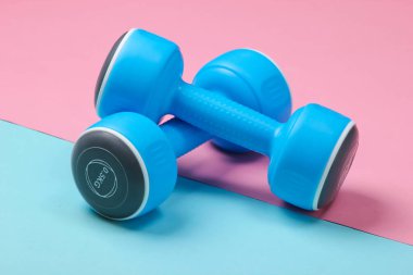 Mavi, pembe renkli arka planda plastik halterler..