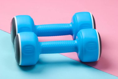 Mavi, pembe renkli arka planda plastik halterler..