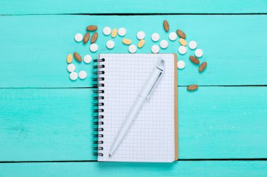 Mavi ahşap arka planda defter olan haplar. Üst görünüm