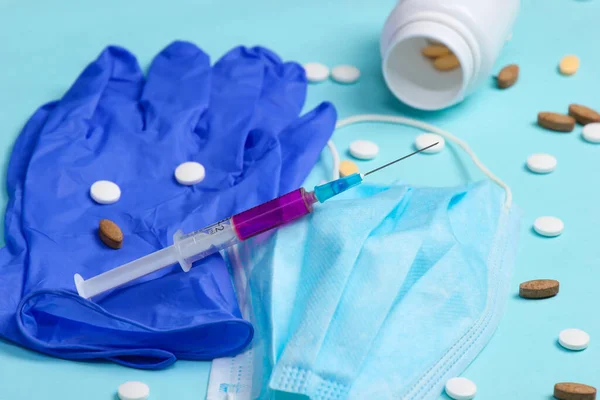 Medical supplies. Syringe, medical gloves, mask, pills on a blue background.
