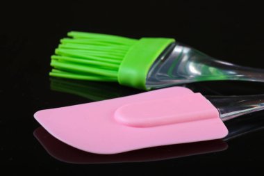 Silikon mutfak spatulası ve siyah arka planda fırça..