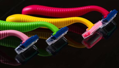 Siyah arkaplanda yansıması olan renkli plastik jiletler.