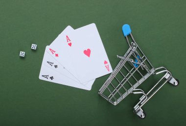 Yeşil arka planda dört as ve zar bulunan bir alışveriş arabası. Üst görünüm