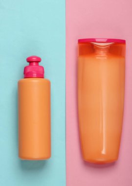 Şampuan şişeleri, pembe mavi arka planda duş jeli. Deri ve saç bakımı. Hijyen ve kozmetik. Güzellik düzlüğü. Üst görünüm