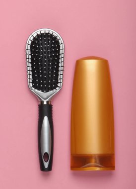 Pembe pastel arka planda şampuan şişeli saç fırçası. Saç bakımı. Hijyen. Güzellik düzlüğü. Üst görünüm