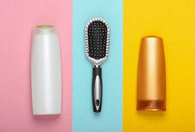 Renkli pastel arka planda şampuan şişeli saç fırçası. Saç bakımı. Hijyen. Güzellik düzlüğü. Üst görünüm
