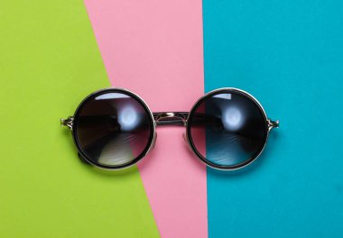 Renkli kağıttan bir arka planda yuvarlak güneş gözlüğü. Minimalizm. Üst görünüm