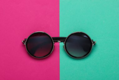 Pembe kağıt arka planda zarif, yuvarlak güneş gözlükleri. Üst Manzara. Minimalizm