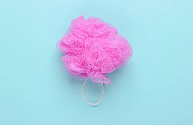 Mavi pastel arka planda pembe banyo süngeri. Üst Manzara. Minimalizm