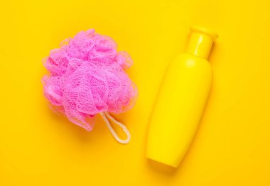 Banyo, sarı arka planda güzellik ürünleri. Duş jeli şişesi ve sünger. Üst Manzara. Düz yatıyordu