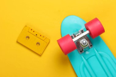 Kruvazör tahtası ve sarı arka planda retro ses kaseti. 80 'ler. Üst Manzara. Minimalizm. Pastel renk eğilimi
