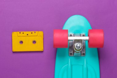 Kruvazör tahtası ve mor arka planda retro ses kaseti. 80 'ler. Üst Manzara. Minimalizm. Pastel renk eğilimi