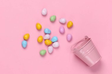 Paskalya yumurtaları ve pembe pastel arka planda mini bir kova. Paskalya minimalizmi. Pastel renk eğilimi