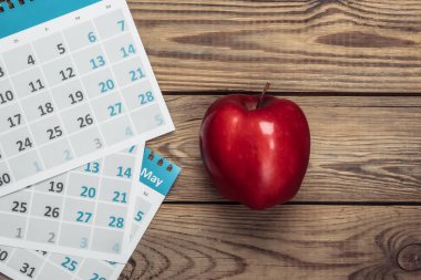 Ahşap arka planda kırmızı elmalı aylık takvim. Üst görünüm